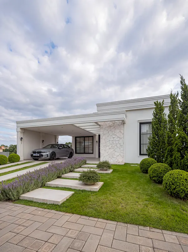 Fachada da Casa Merlot vista do jardim, com caminho em placas, lavandas e buxinhos