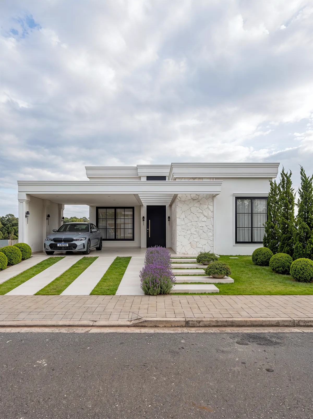 Fachada da Casa Merlot: casa térrea branca de linhas neoclássicas, com pórtico, pedra natural e jardim com lavandas