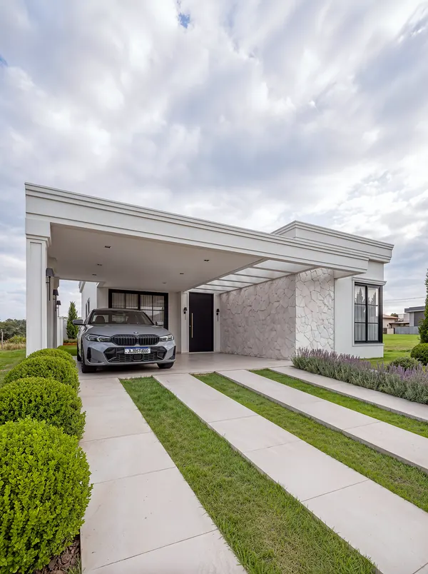 Pórtico da garagem com molduras neoclássicas, painel em pedra natural e entrada pavimentada